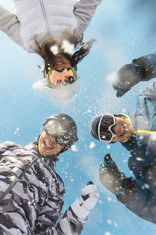 三个青年男女在户外滑雪场扔雪花嬉戏玩耍图片下载