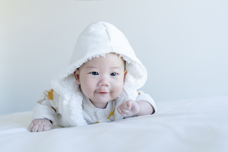 穿白色连帽马甲的宝宝俯卧表情图片下载