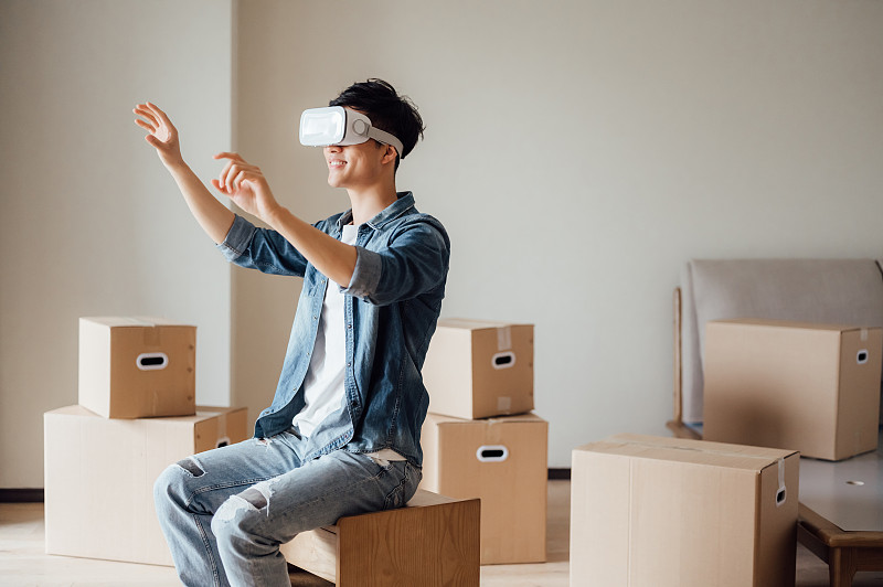 亚洲年轻男孩在新家使用VR眼镜图片素材