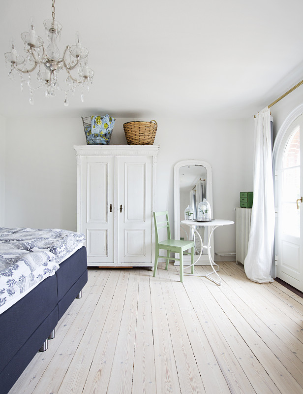 白色衣柜，圆桌和椅子，浅色木地板的卧室双人床图片下载