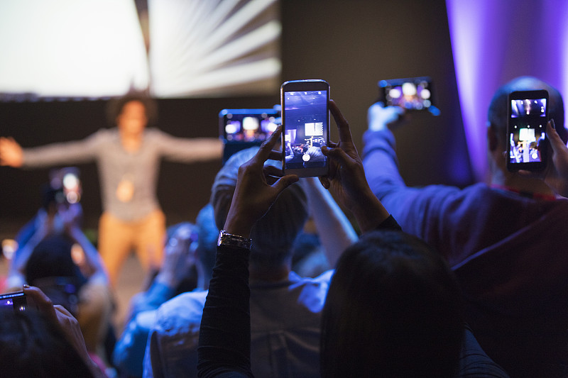 观众用照相手机拍摄舞台上的演讲者图片素材