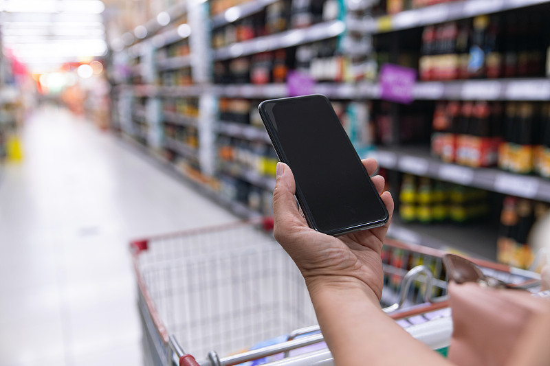 中年女性拿着手机在超市购物图片下载