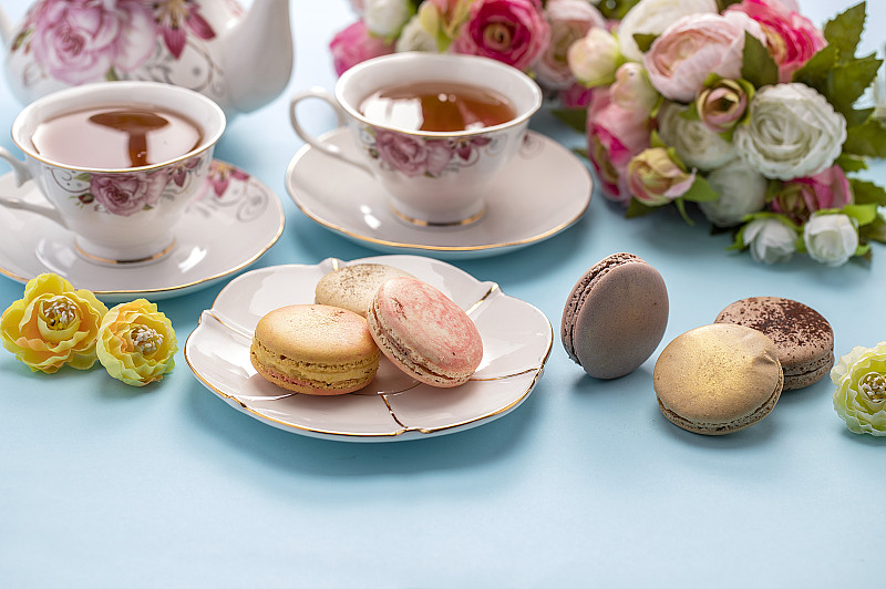 红茶和许多色彩鲜艳的马卡龙摆放在桌上图片下载