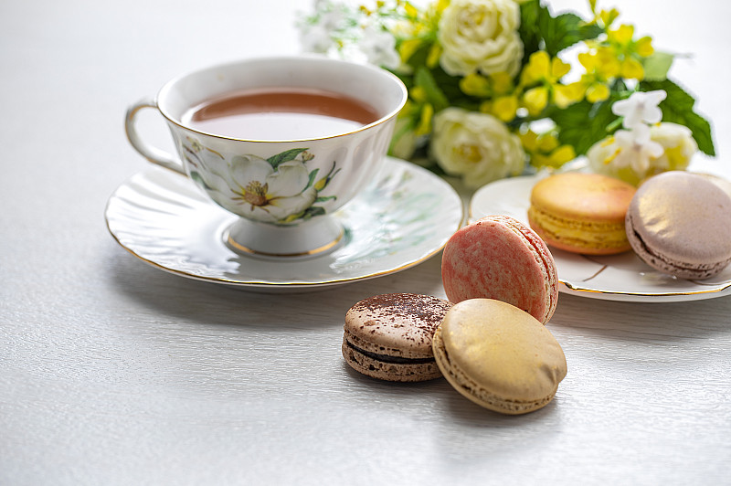 红茶和许多色彩鲜艳的马卡龙摆放在桌上图片素材