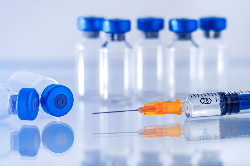 蓝色背景下的疫苗瓶和注射器图片下载
