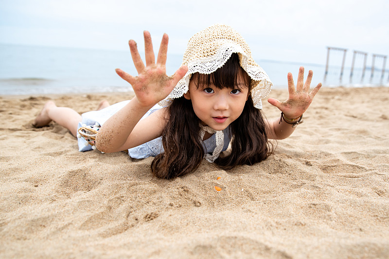 趴在海滩上玩耍的小女孩图片下载