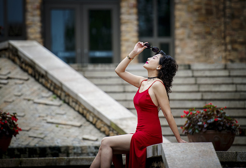一个穿着红色裙子的漂亮女人坐在台阶上图片下载