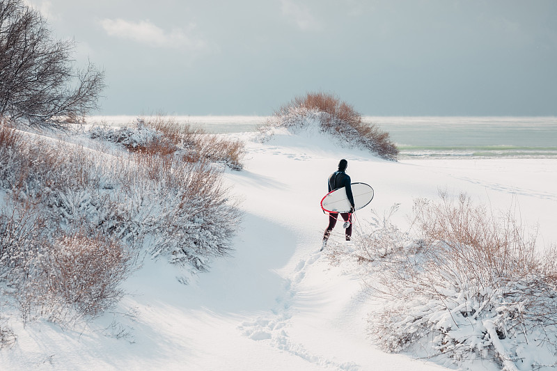 滑雪男子在沙滩上走着冲浪板图片下载