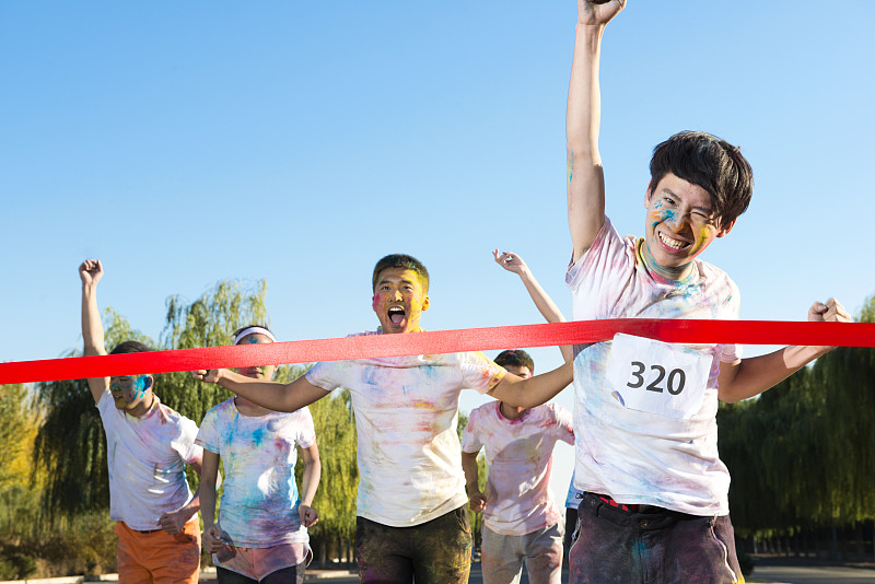 Young man crossing finishing line at The Color Run图片下载