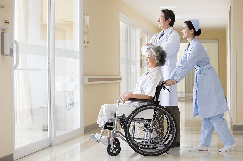 医护人员照顾坐轮椅的老人图片下载