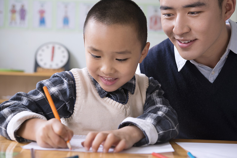 Kindergarten teacher and boy writing图片下载