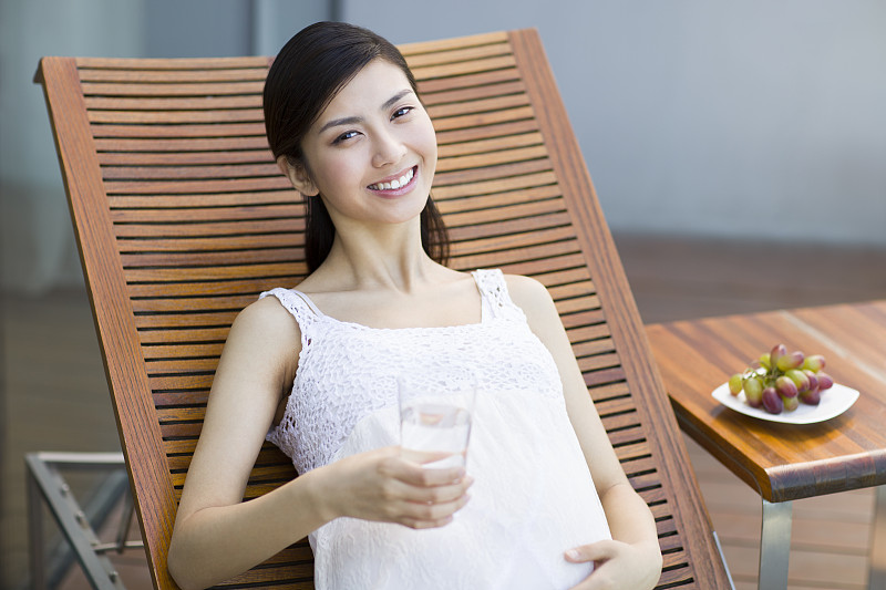 孕妇靠在躺椅上喝水图片下载