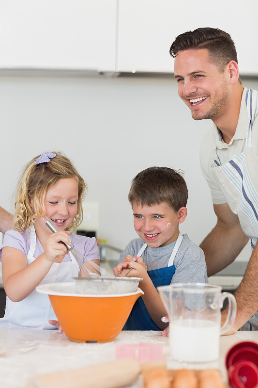 快乐的孩子和父亲在厨房的柜台上烤饼干图片下载