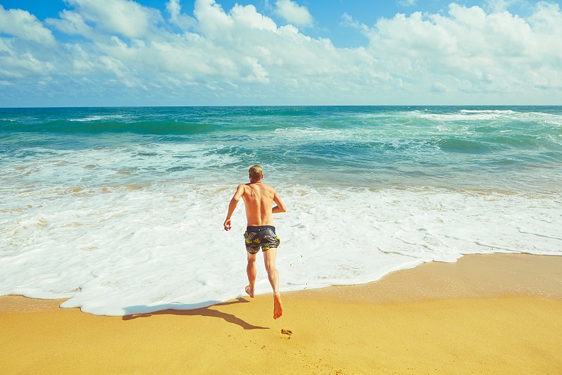 一个男人在海滩上跑步。图片下载
