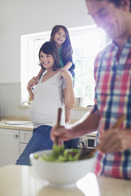 怀孕的母亲和女儿看着父亲扔沙拉图片素材