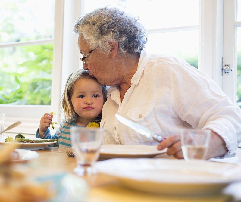 美国加州，小女孩(2-3)和奶奶一起吃晚餐，得到亲吻图片素材