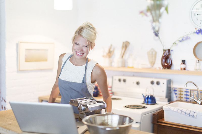 在厨房用笔记本电脑做饭的女人图片下载