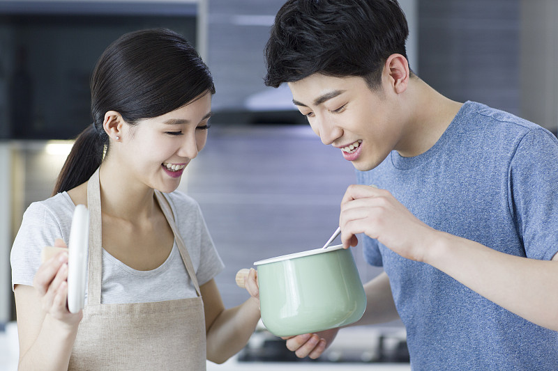 快乐的年轻夫妇在厨房做饭图片素材