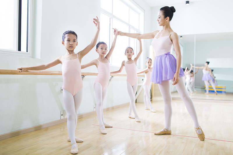 年轻舞蹈老师教小女孩们跳芭蕾图片下载