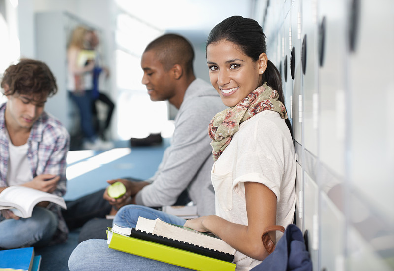 一个微笑的大学生坐在走廊的地板上图片下载