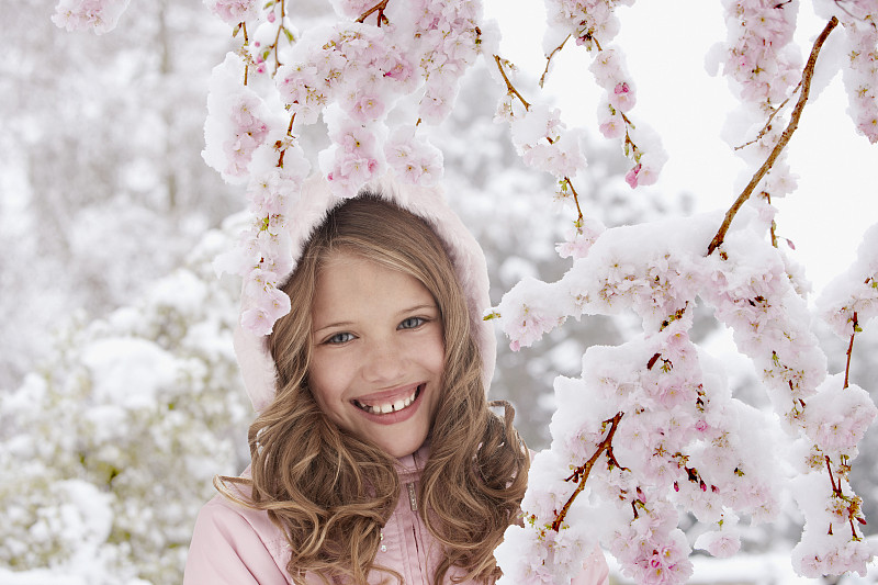 微笑的女孩站在开花的树下图片素材