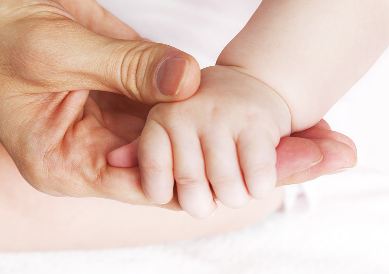 母亲牵着婴儿的手。美丽，柔软和微小。保护。图片下载