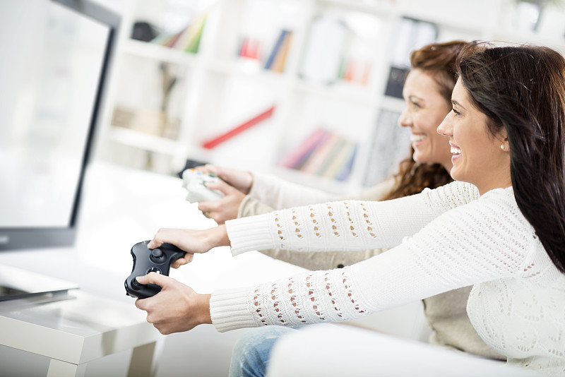 母亲和女儿玩电子游戏图片下载