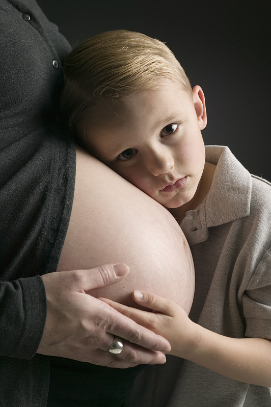男孩(4-5)把耳朵贴在孕妇的肚子上，肖像图片下载
