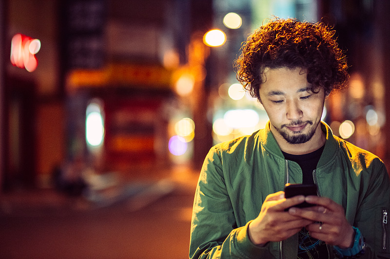 年轻的日本青少年在城市场景中拿着手机图片下载