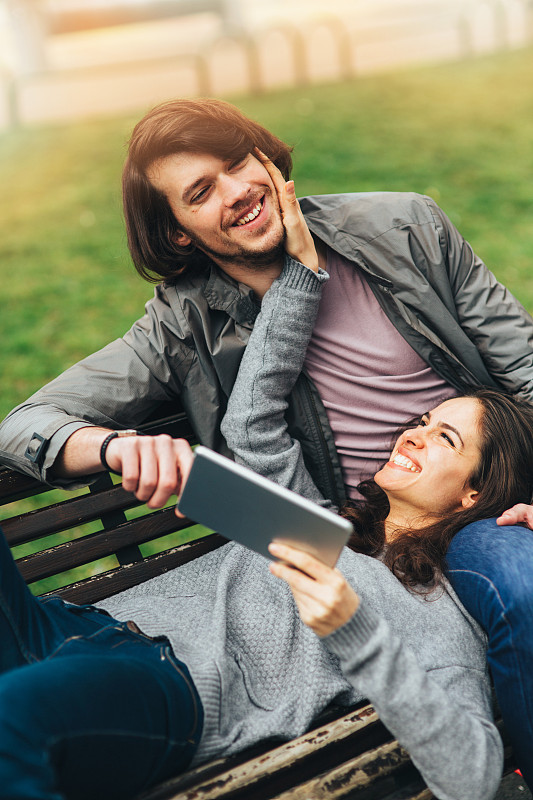 快乐的年轻夫妇玩一个数字平板电脑图片下载