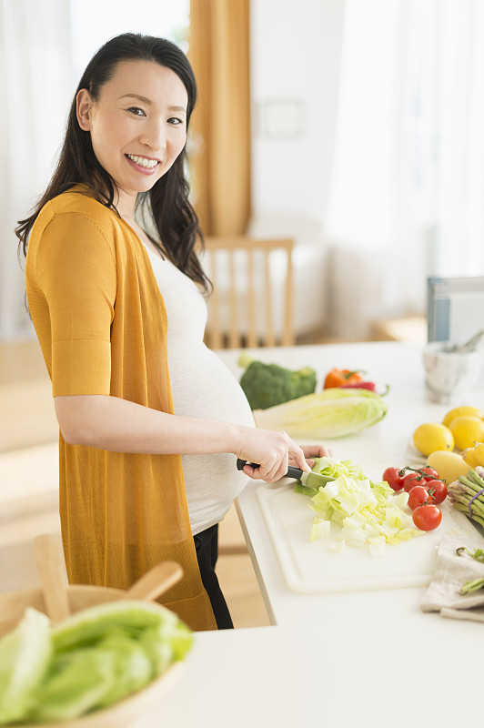 日本孕妇在厨房切蔬菜的照片摄影图片