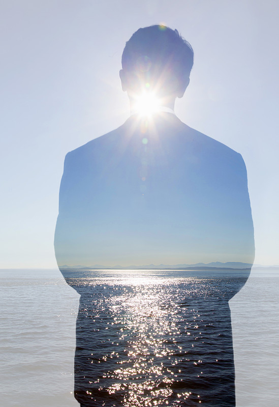 双重曝光:海面上的人与太阳爆发。图片下载