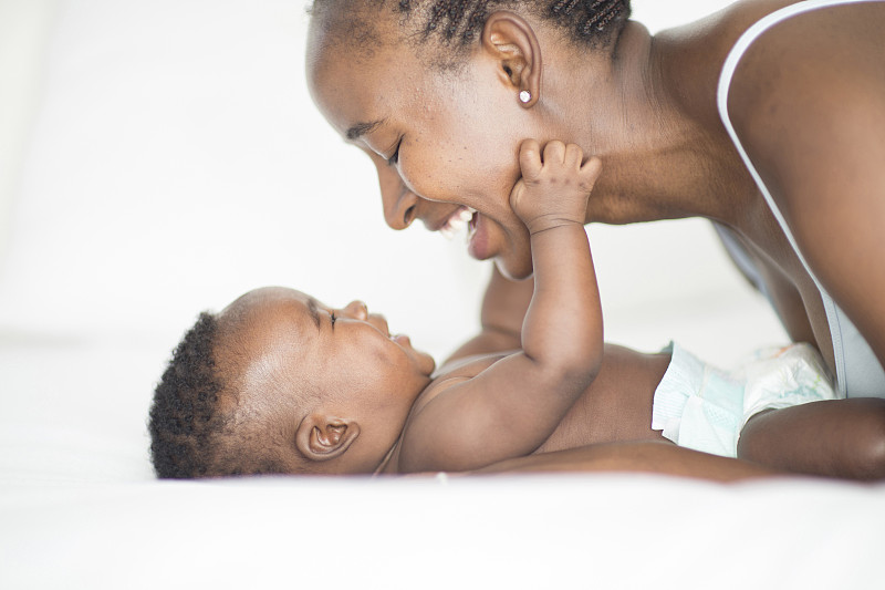黑人妈妈和婴儿在床上玩图片下载