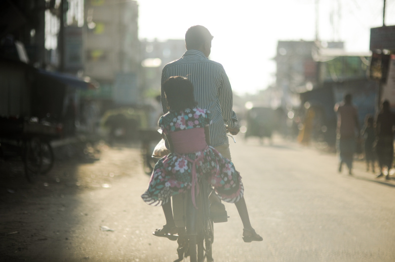 父亲和女儿在街上骑自行车的后视图图片素材