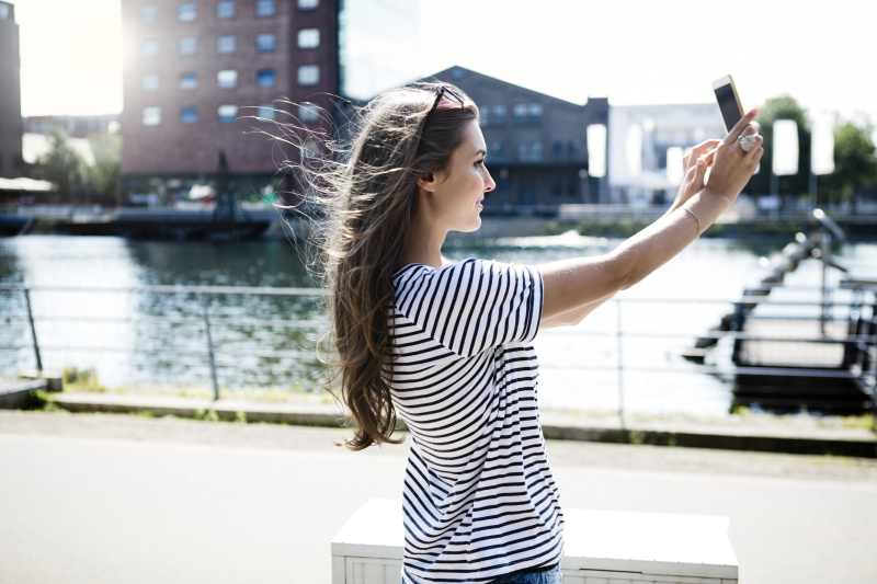 德国杜伊斯堡，一名年轻女子在用智能手机自拍图片下载