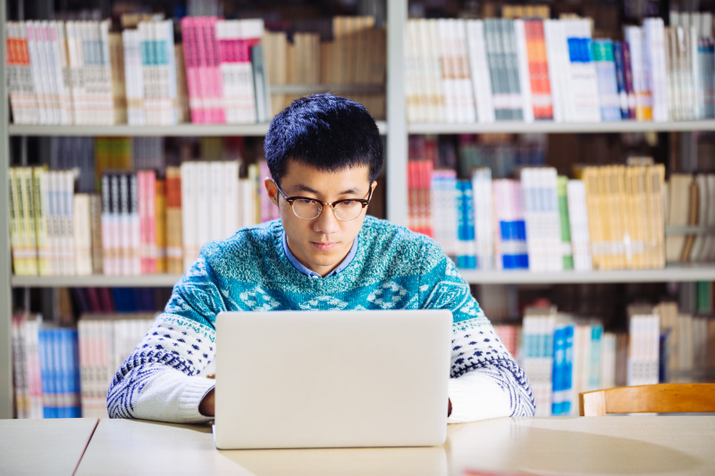 年轻的亚洲人在图书馆用笔记本电脑图片下载