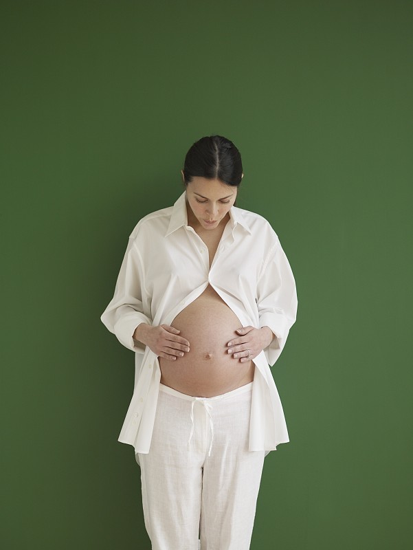 孕妇抱着并看着裸露的肚子图片下载