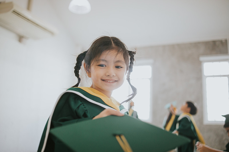 泰国可爱的宝贝女孩收到她的毕业帽与毕业日股票照片摄影图片
