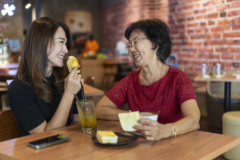 快乐的母亲和女儿在咖啡厅享受下午茶时间图片下载