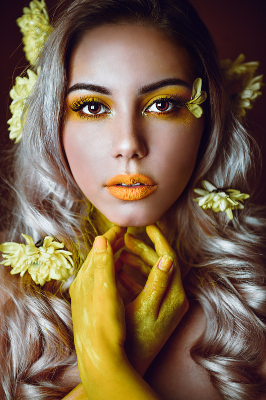 美丽的女性与花在头发和黄色化妆图片下载