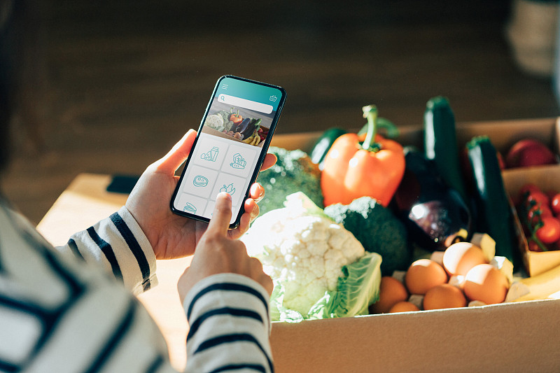年轻女子用智能手机在网上订购食品杂货图片素材