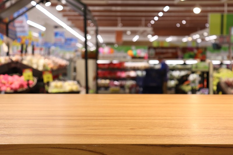 超市里空荡荡的木桌，模糊的购物中心形象。图片素材