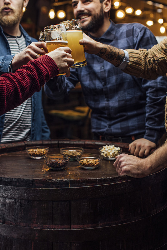 一群男人在酒吧与啤酒干杯，一个近距离图片素材