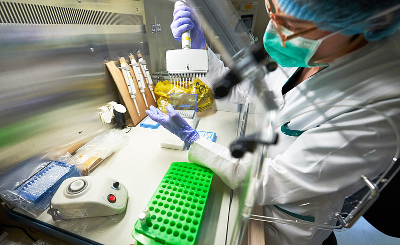 科学家利用医用防护，用物质和实验，移液管小瓶在实验室微生物分离器用于病理实验室的PCR诊断试验。图片素材