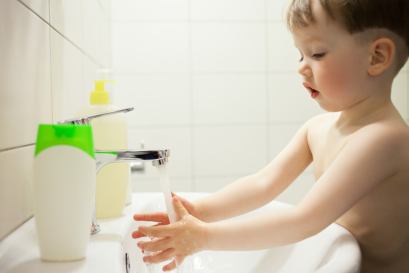 2岁的小男孩在浴室用肥皂洗手图片素材