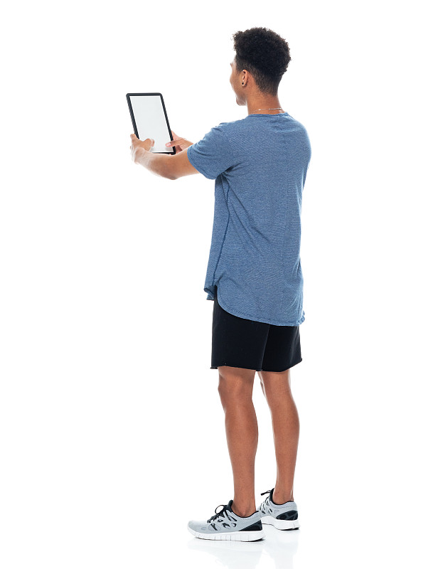 非裔美国青年男性穿着t恤站在白色背景前，使用数码平板电脑图片下载