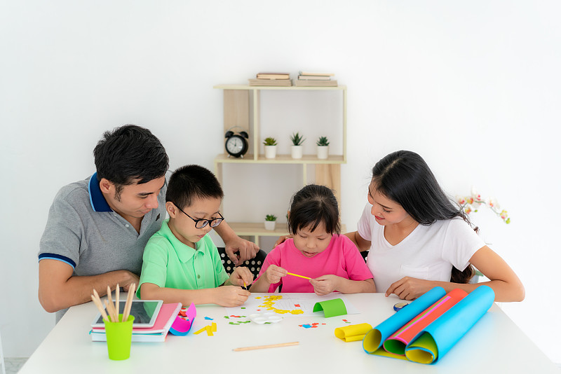 亚洲家庭与父亲，母亲，女儿和儿子编辑彩色纸制作艺术品，并参与手工艺项目和奖励活动在家自学。图片下载