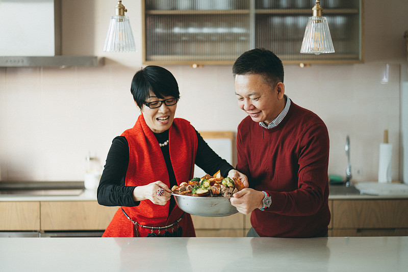 资深亚洲夫妇拿着美味的自制传统中国菜，与家人分享农历新年团圆饭图片下载