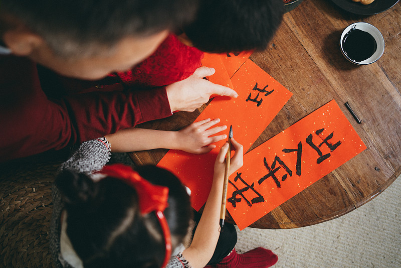 俯视图快乐的小孙女和孙子练习书法，为中国新年的对联与他们的祖父图片素材
