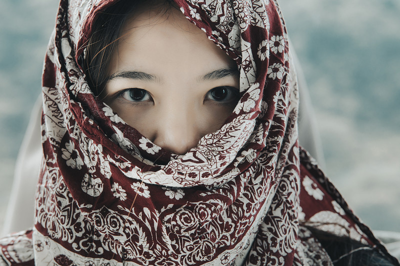 一名亚洲华人妇女的头像照片，她的头巾盖住了嘴摄影图片